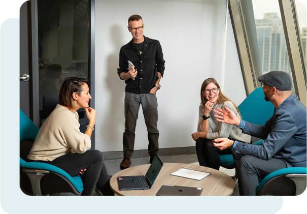 A diverse group of professionals engaged in discussion around a conference table in a modern office setting.