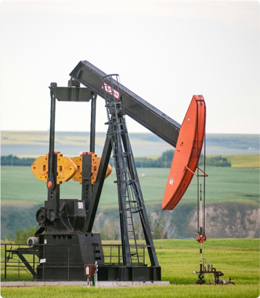 Oil pump jack in a green field landscape.